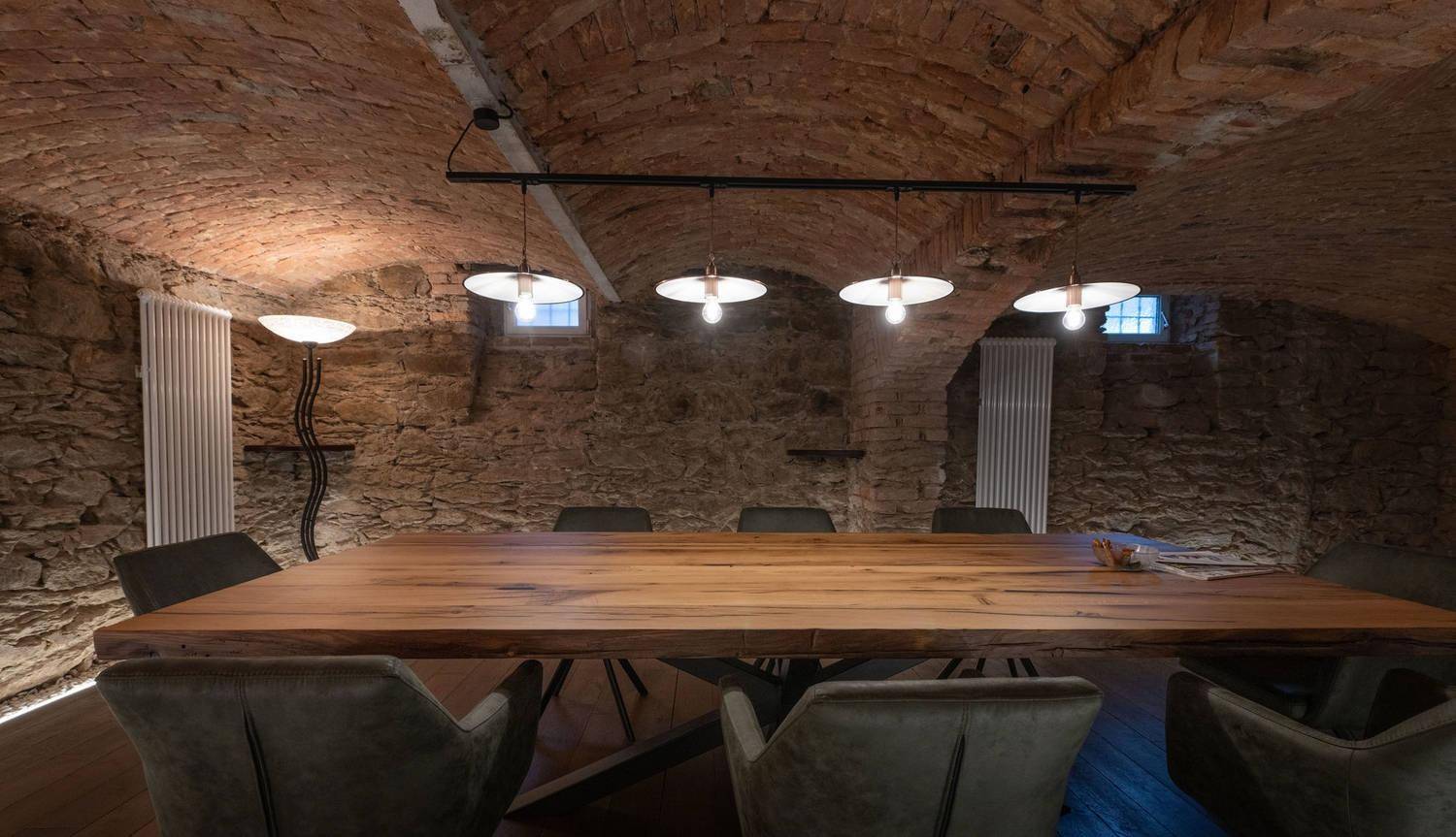 Rustikaler Essbereich im Gewölbekeller mit Ziegelwänden und Holztisch.