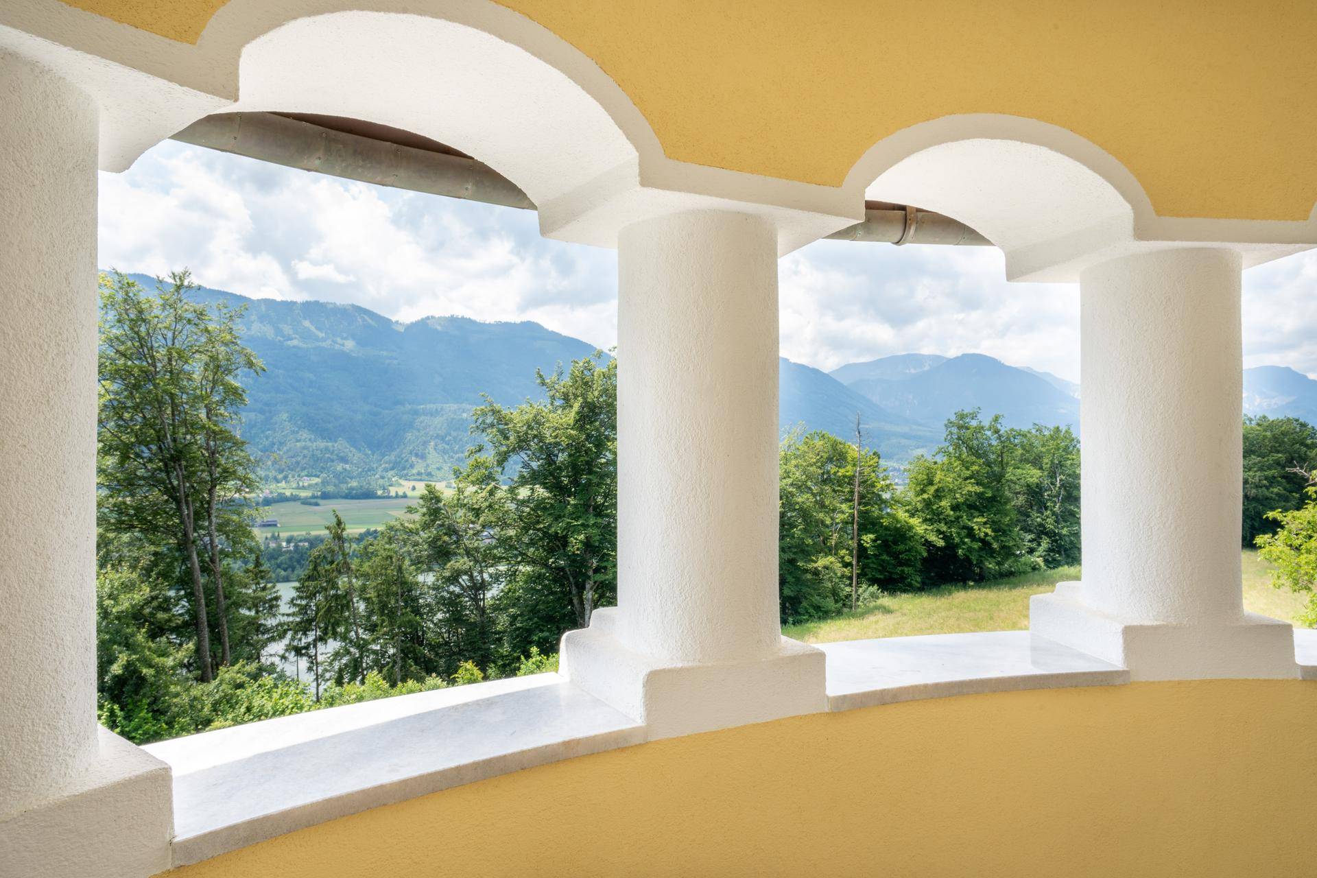 Blick von der Loggia auf eine malerische Berglandschaft mit üppigem Grün und weitem Horizont.