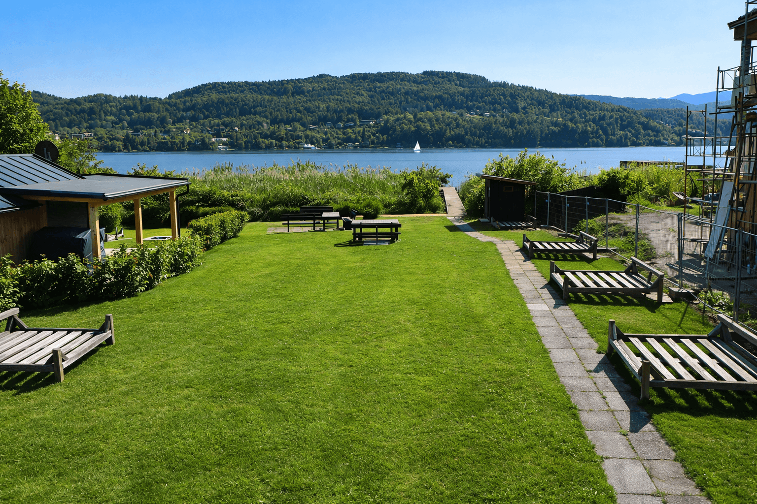 Großer Rasengarten mit Liegestühlen und Picknicktischen, direkt am See gelegen mit Bergblick.