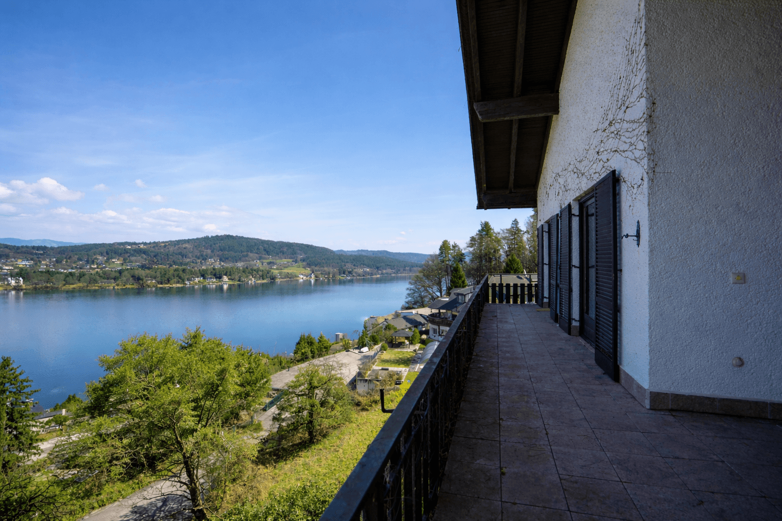 Geräumiger Balkon mit Fliesenboden und weitem Blick über den See und die grünen Hügel.