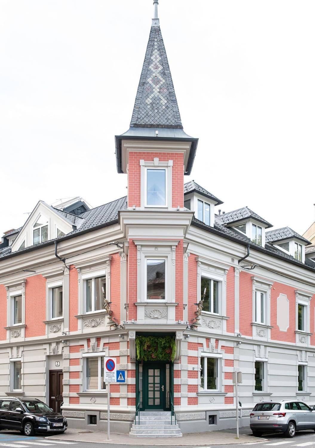 Detailansicht der historischen Fassade mit Turm und dekorativen Elementen bei Tageslicht.
