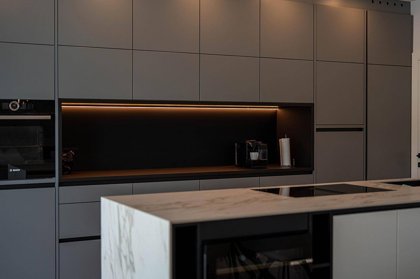 Hochwertige Einbauküche mit modernen Geräten, Induktionskochfeld und eleganter Marmorarbeitsplatte.