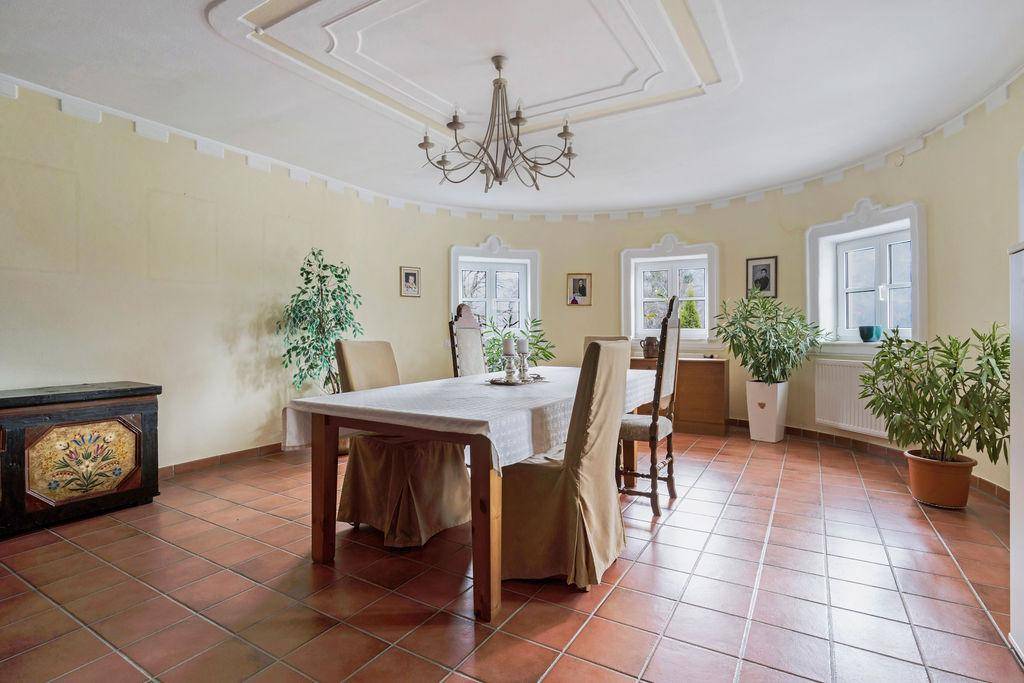 Eleganter Essbereich mit großem Tisch, Terrakottaboden und dekorativer Decke.