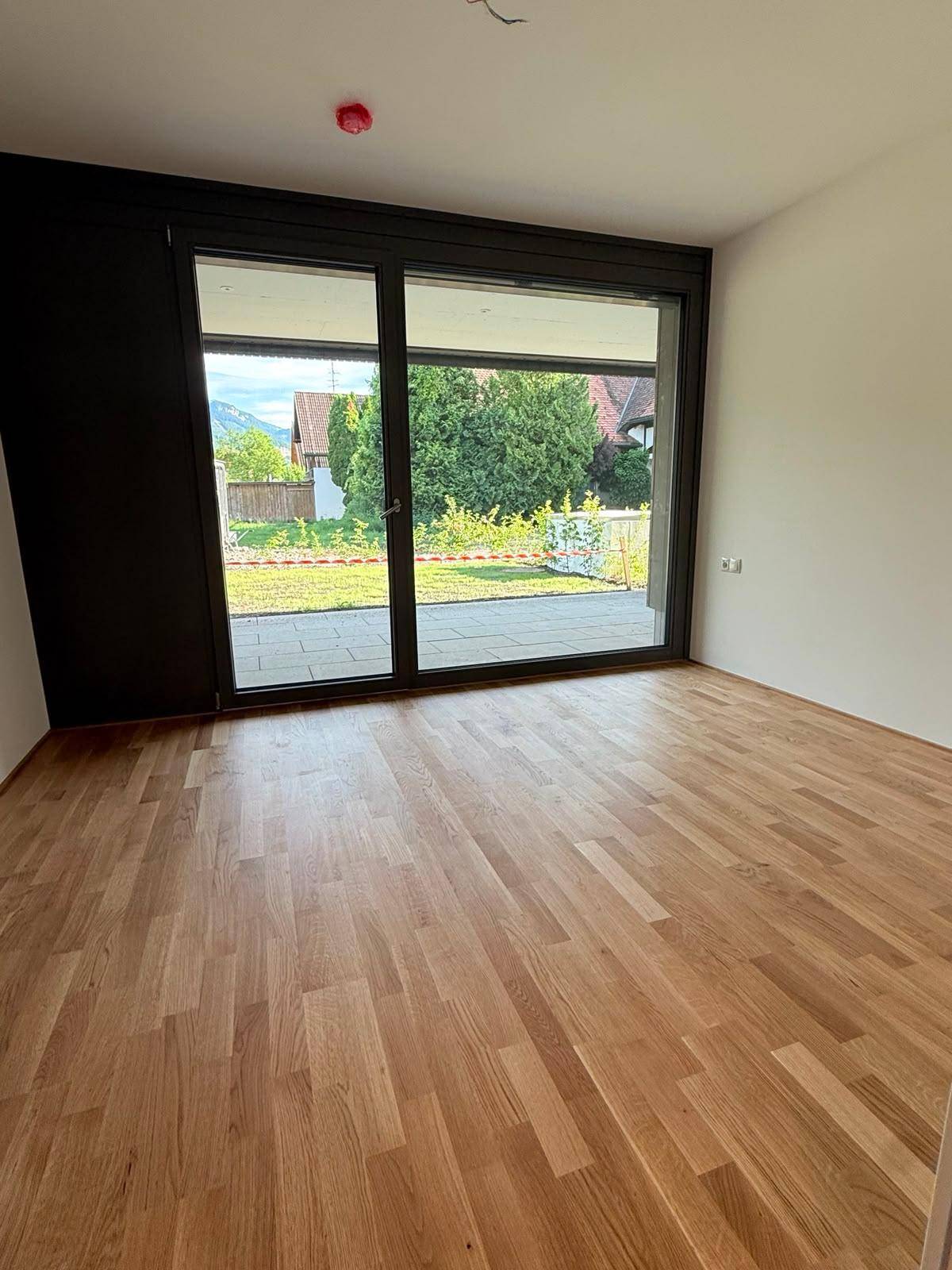Geräumiger, heller Raum mit Parkettboden und großer Schiebetür, die zur Terrasse führt.