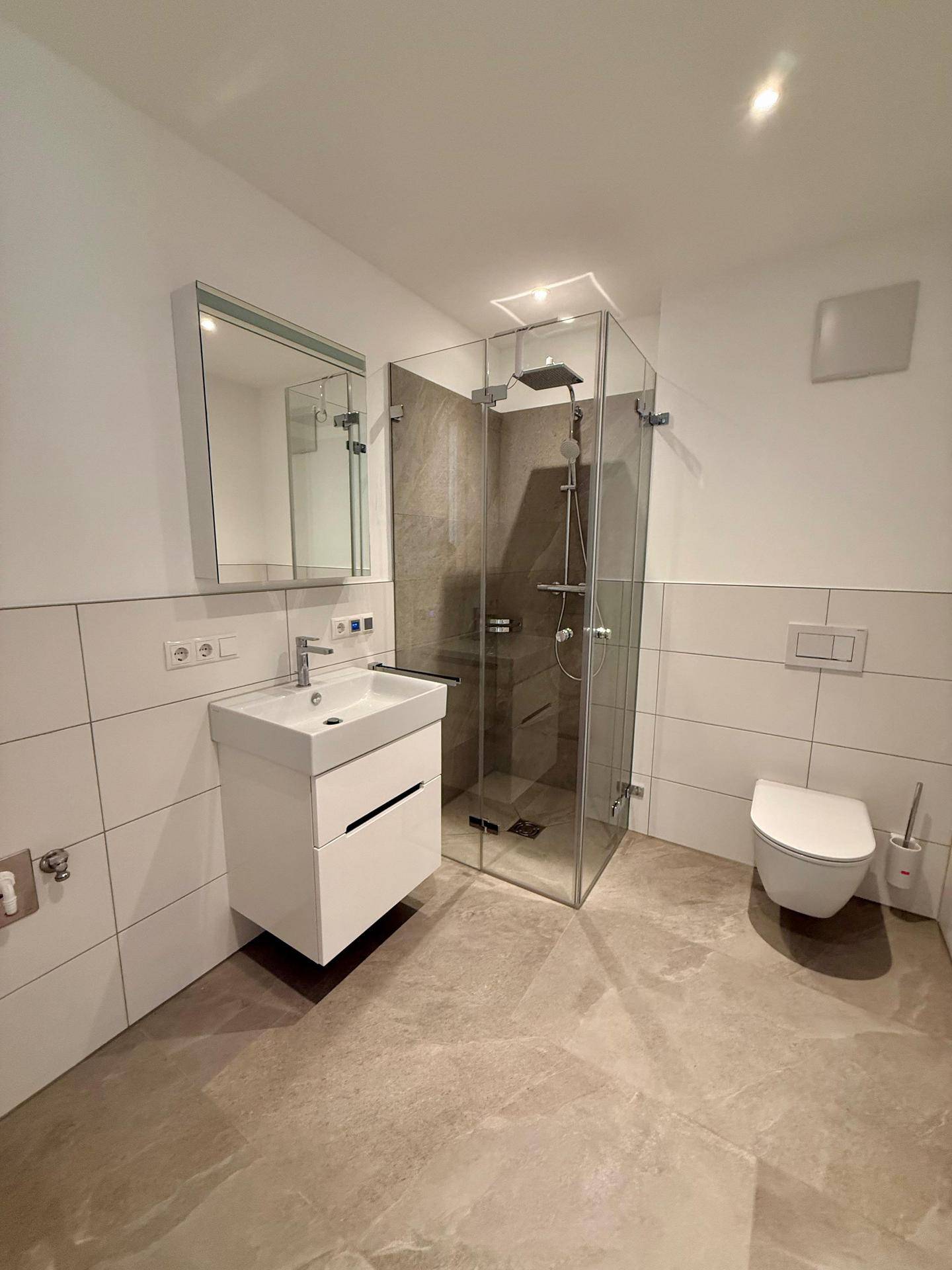 Modernes Badezimmer mit begehbarer Dusche, Wand-WC und eleganten Fliesen.