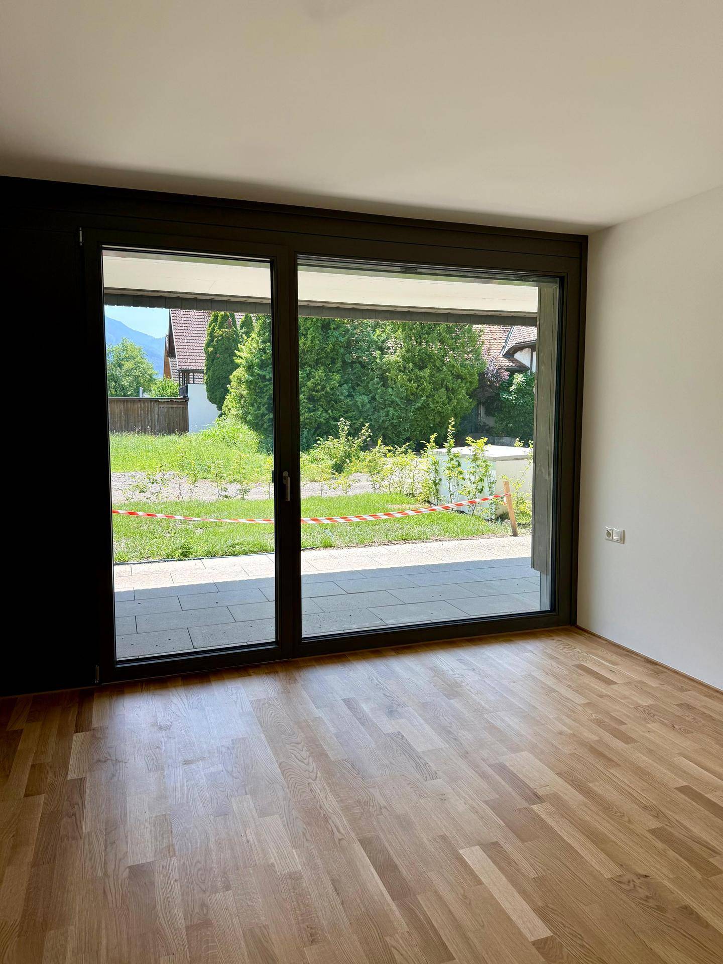 Lichtdurchfluteter Raum mit großen Schiebetüren, Parkettboden und Blick in den Garten.