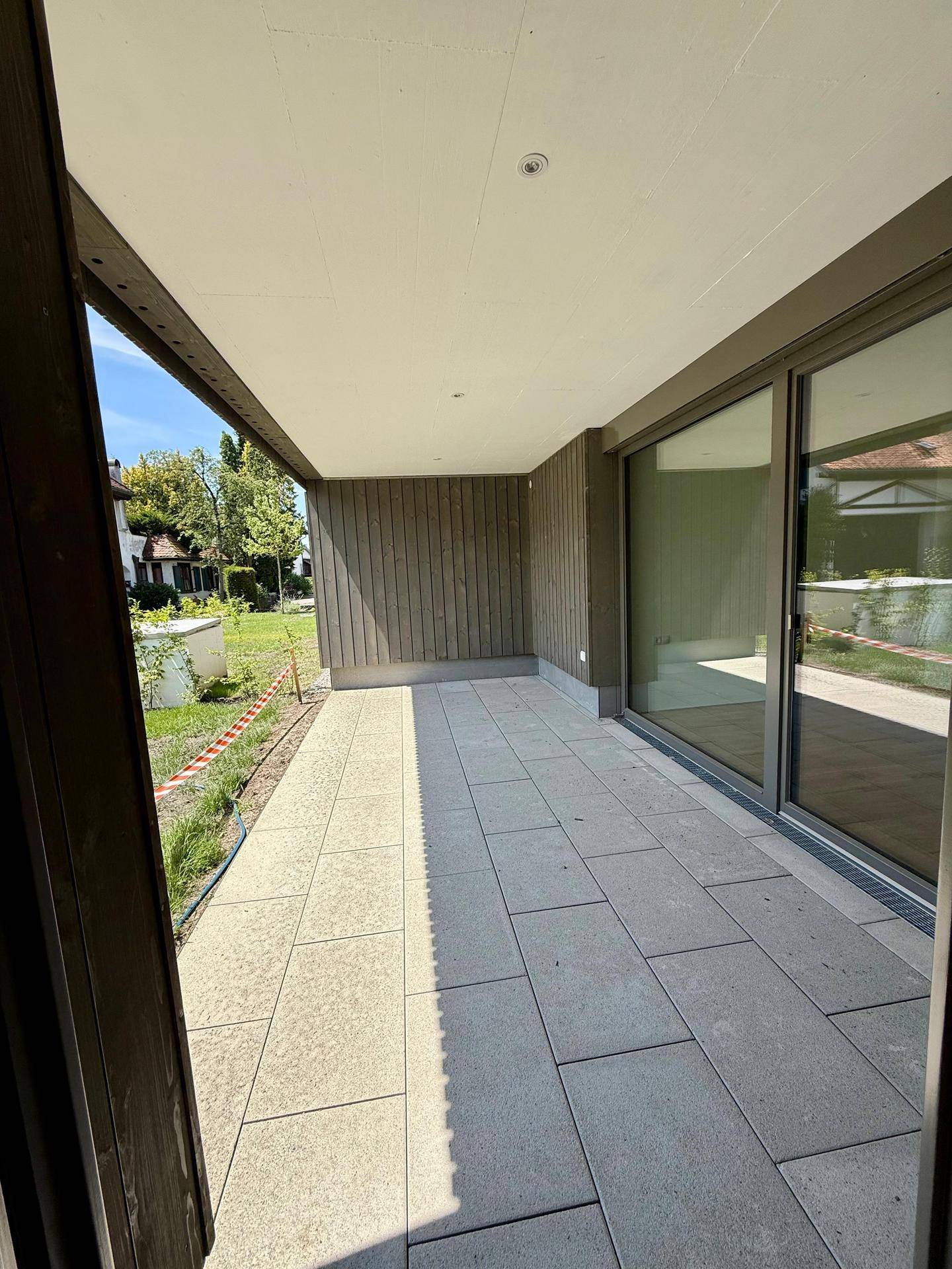 Überdachte Terrasse mit Fliesenboden und direktem Zugang zum privaten Gartenbereich.
