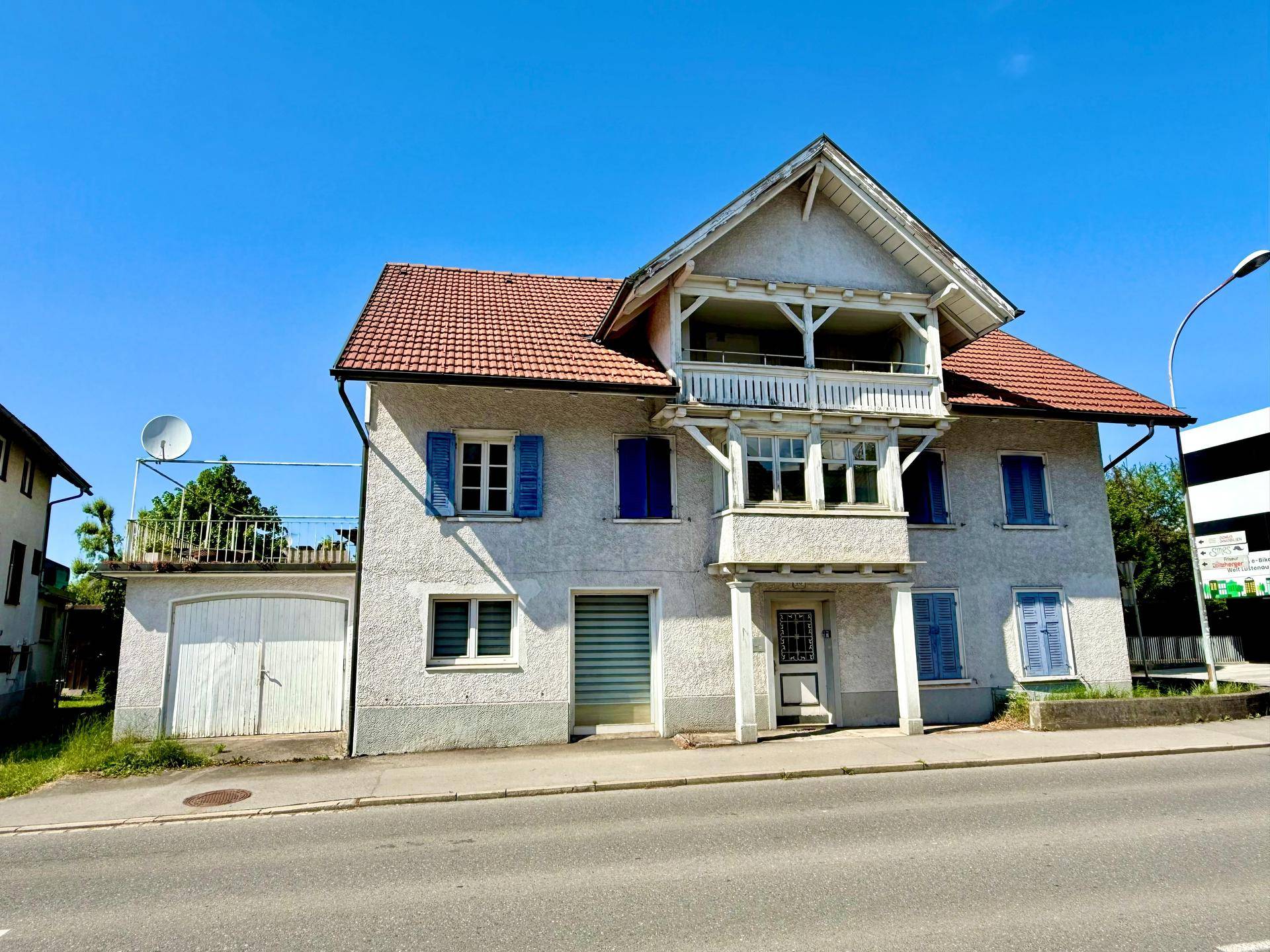 Frontansicht des charmanten Wohnhauses mit traditionellen blauen Fensterläden und Satteldach.