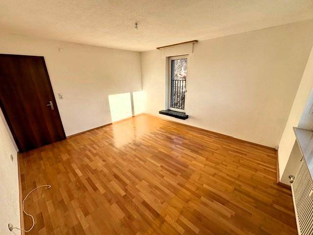 Helles Schlafzimmer mit Parkettboden und Zugang zu einem französischen Balkon.