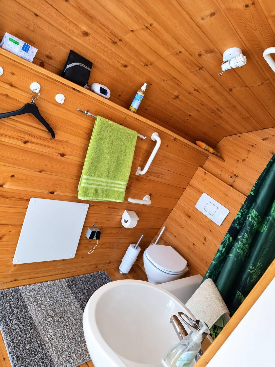 Kleines Badezimmer mit Holzverkleidung, Waschbecken und Toilette unter Dachschräge.