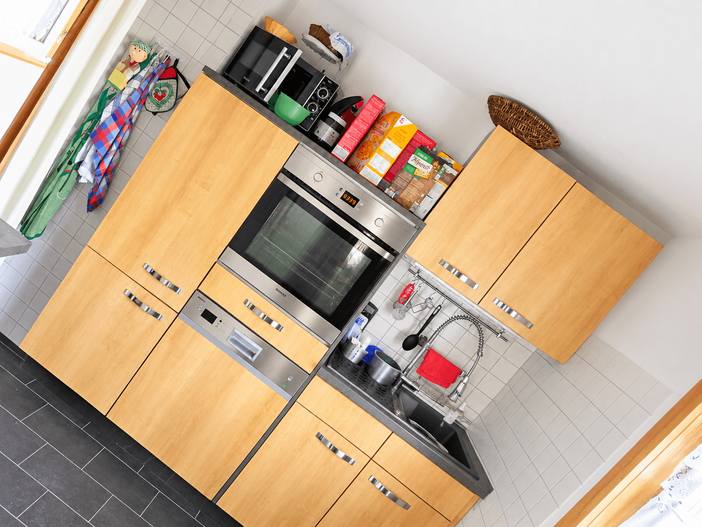 Funktionale Küche mit Holzfronten, integriertem Backofen und Geschirrspüler.