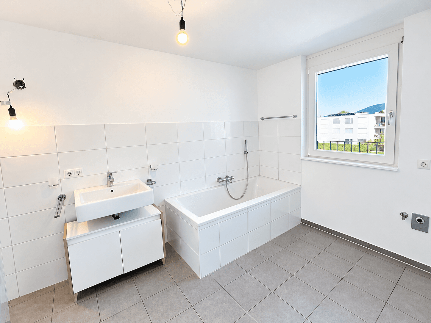 Helles Badezimmer mit Badewanne, Einzelwaschbecken und Fenster für Tageslicht.