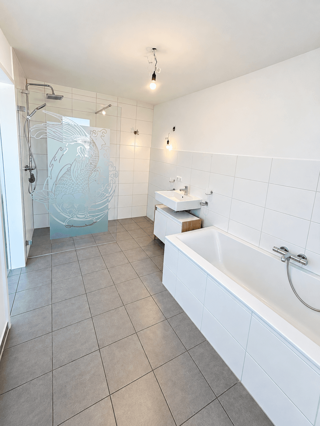 Modernes Badezimmer mit Badewanne, begehbarer Dusche und eleganten Fliesen in Weiß und Grau.