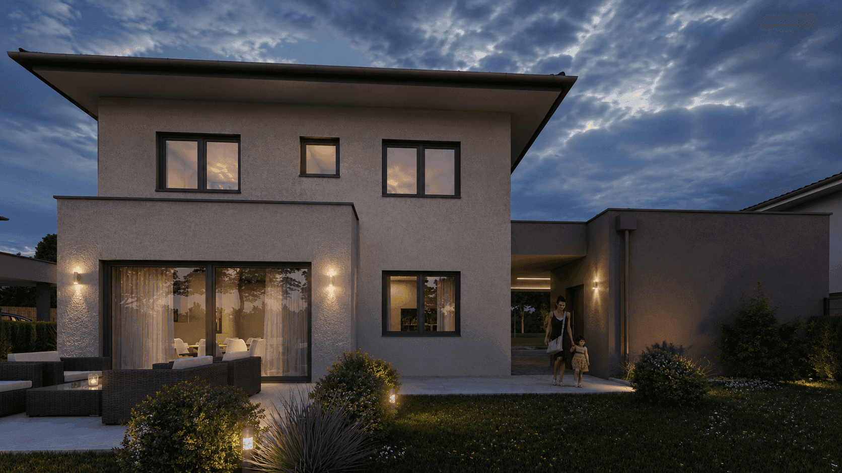 Nachtansicht des modernen Einfamilienhauses mit beleuchteter Terrasse und gepflegtem Garten unter bewölktem Himmel.