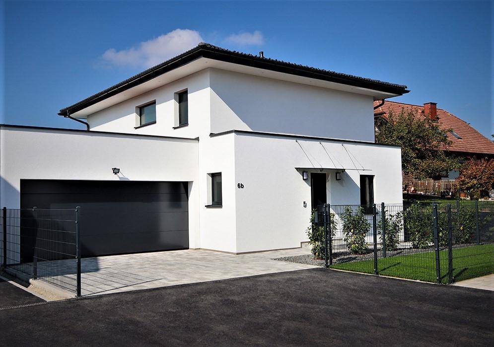 Moderne Hausfassade mit integrierter Doppelgarage und gepflasterter Auffahrt.