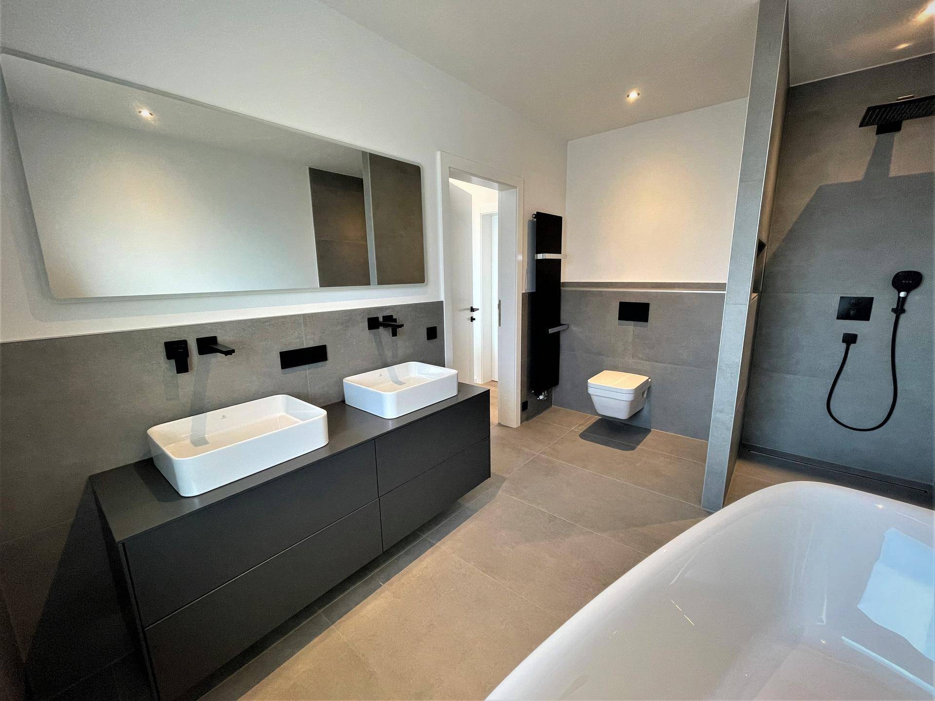 Elegantes Badezimmer mit Doppelwaschbecken, begehbarer Dusche und beheiztem Handtuchhalter.