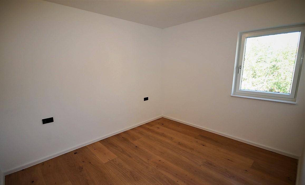 Helles Zimmer mit Holzboden und einem Fenster, das viel Tageslicht hereinlässt.