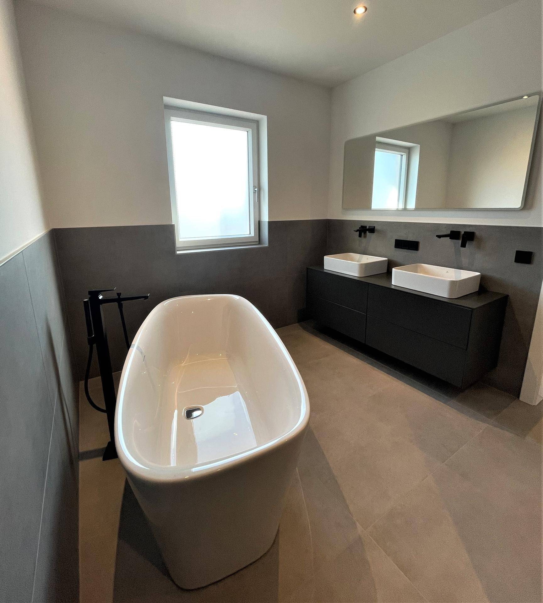 Luxuriöses Badezimmer mit freistehender Badewanne, Doppelwaschbecken und großem Spiegel.