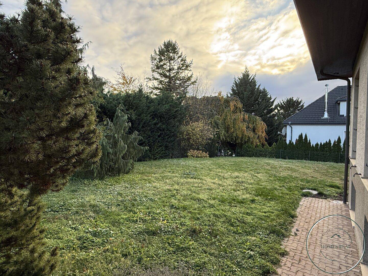 Weitläufiger Garten mit altem Baumbestand und gepflegter Rasenfläche hinter dem Haus.