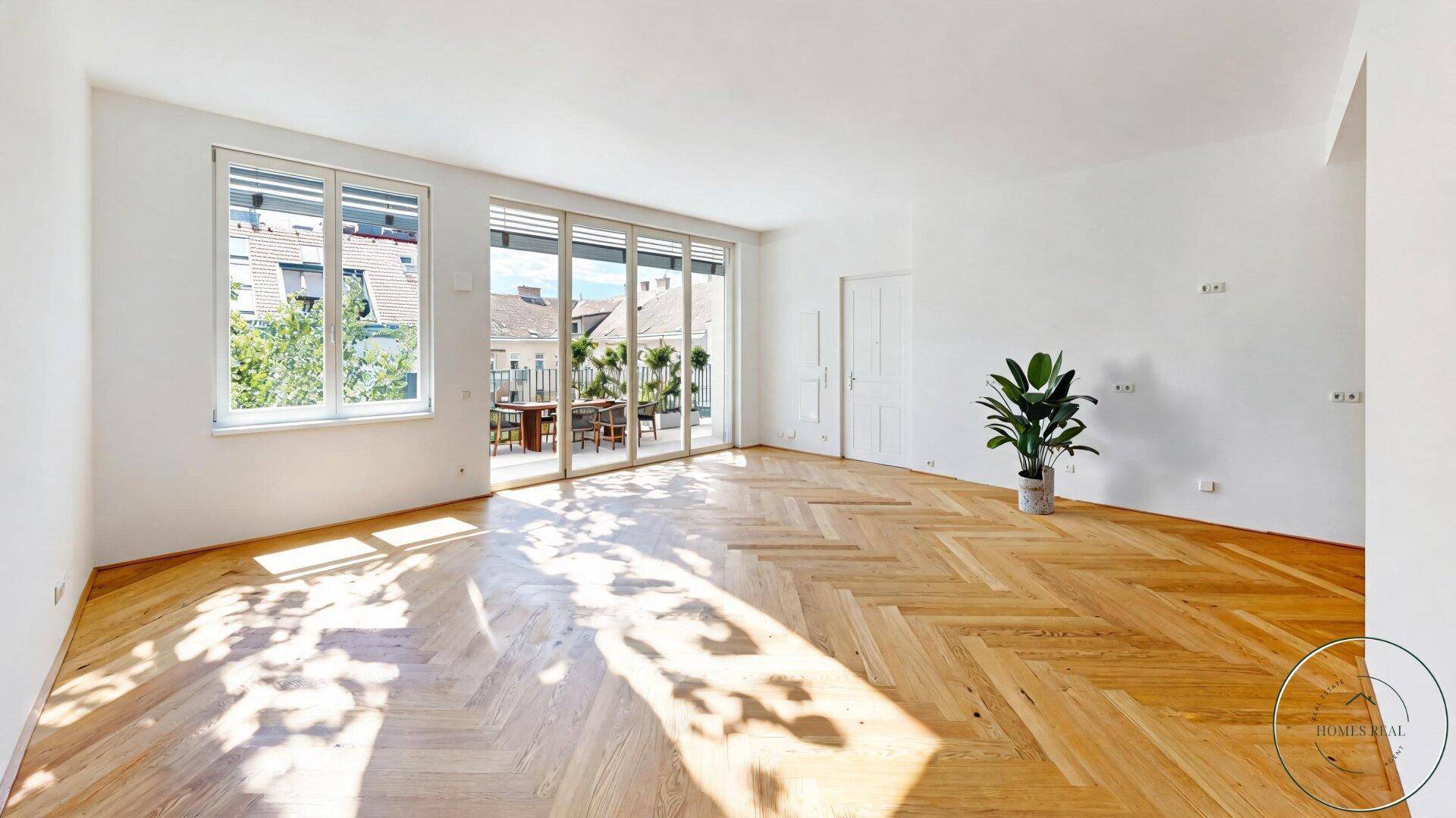 Geräumiges, helles Wohnzimmer mit Fischgrätparkett und großem Zugang zum Balkon.