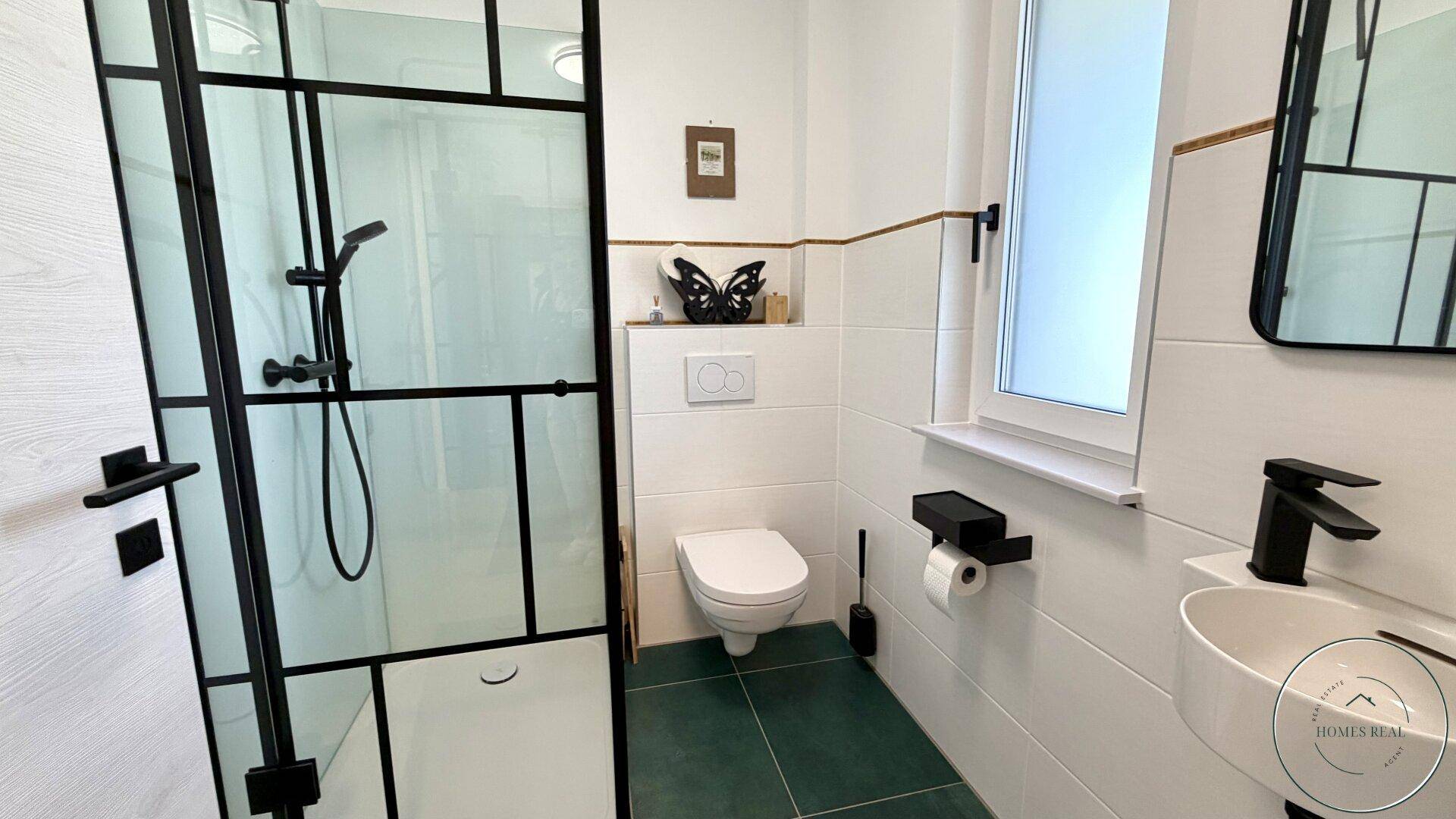 Helles Badezimmer mit moderner begehbarer Dusche, wandhängendem WC und einem einzelnen Waschbecken.