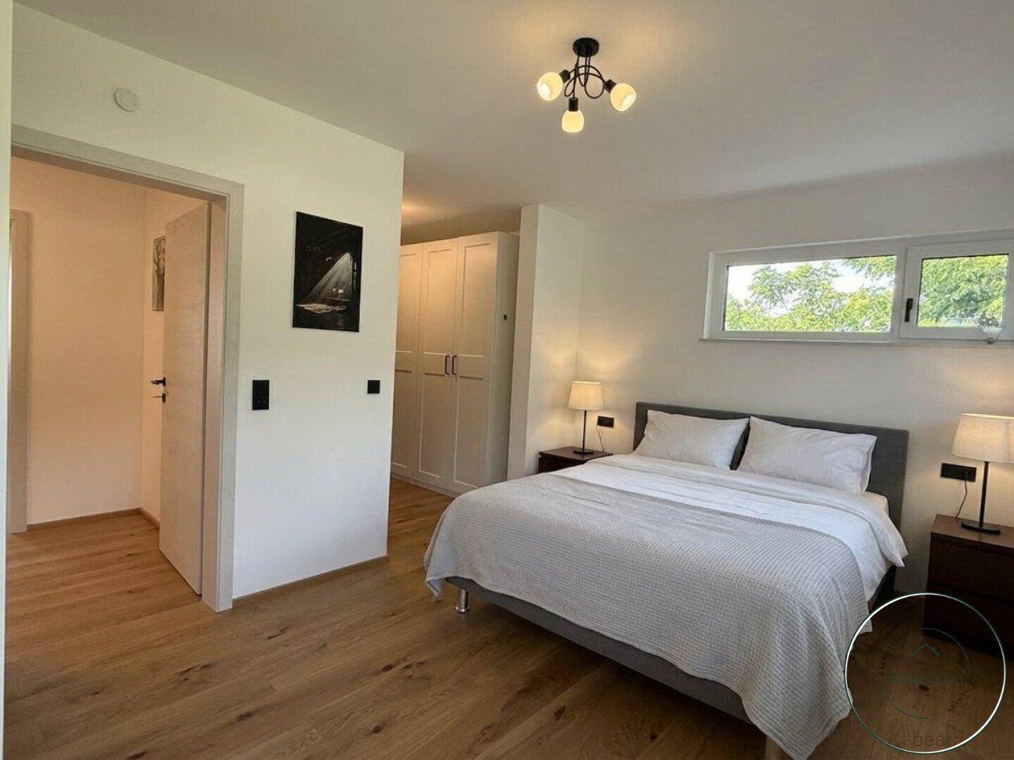 Geräumiges Schlafzimmer mit Doppelbett, Nachttischen und praktischen Einbauschränken, ausgestattet mit Holzfußboden.