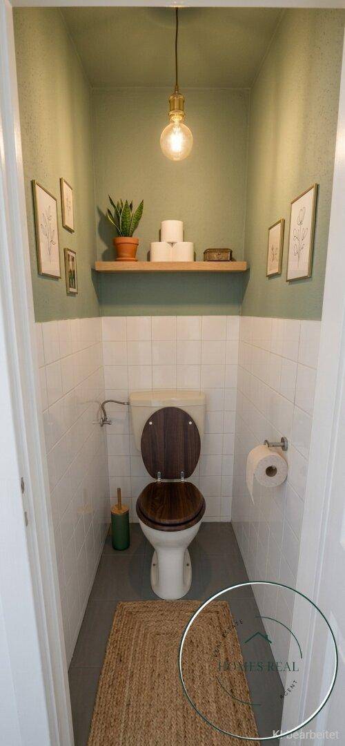 Kompaktes Gäste-WC mit Wandregal, Toilette und schlichtem, funktionalem Design.