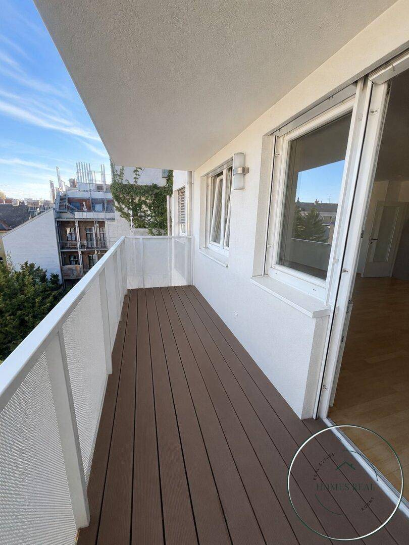 Geräumiger Balkon mit Holzboden und Blick auf die Umgebung, bereit zur individuellen Gestaltung.