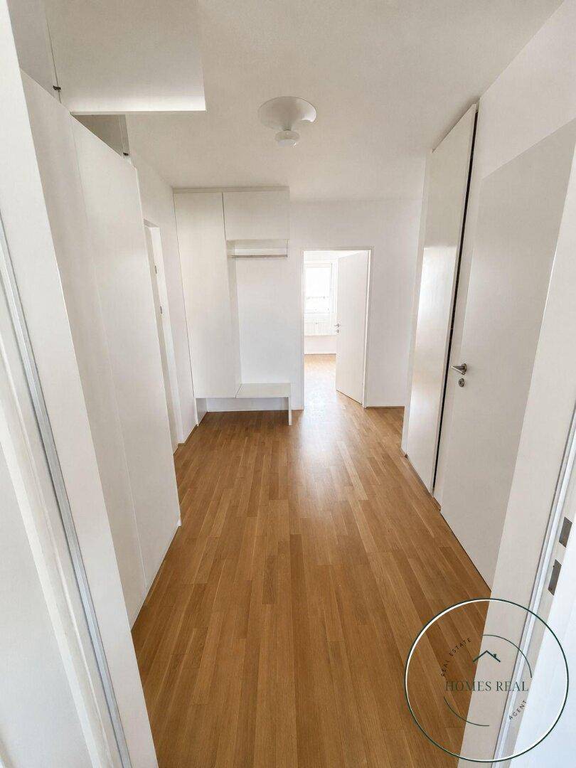 Geräumiger Flur mit Holzboden und viel Platz, ideal für Garderobe und Empfangsbereich.