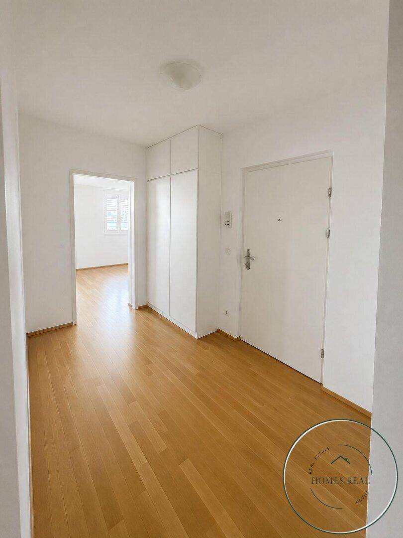 Heller Eingangsbereich mit Holzboden und integrierten Schränken, bietet praktischen Stauraum.