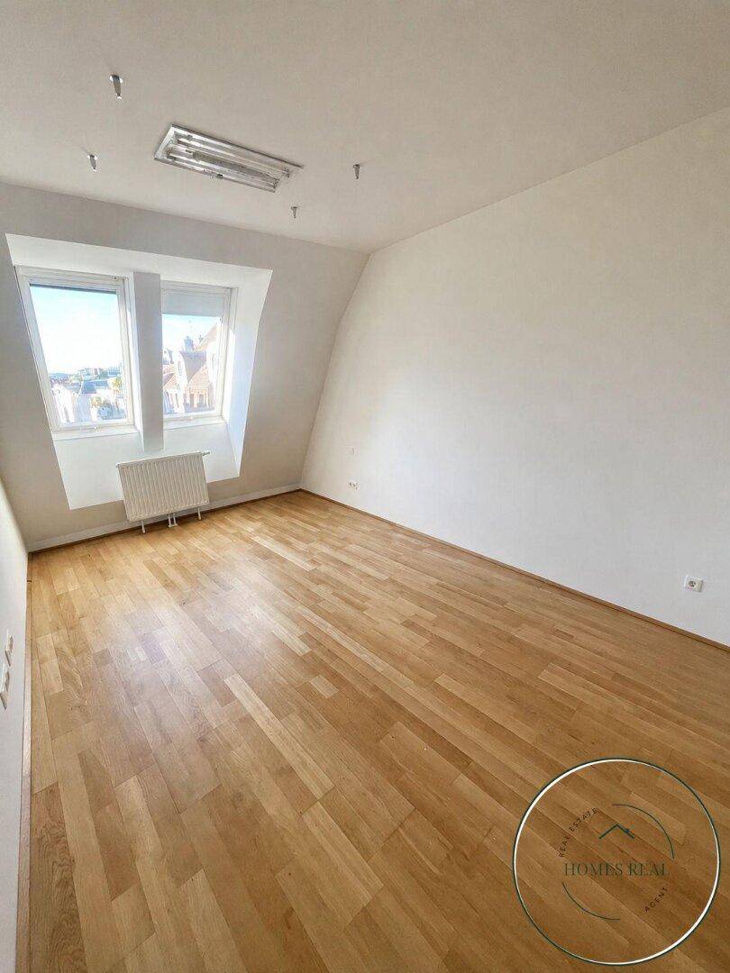 Leeres Schlafzimmer mit Holzboden und Dachfenstern, bietet viel Potenzial für persönliche Gestaltung.