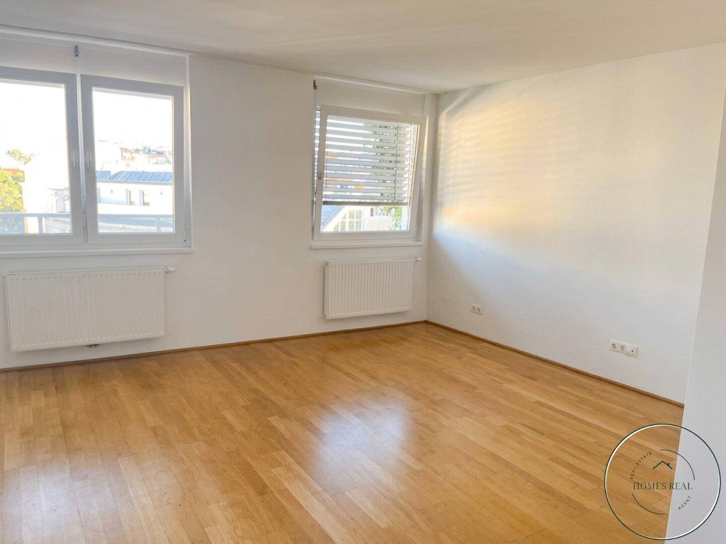 Helles Wohnzimmer mit Holzboden und großen Fenstern, bietet viel Raum für individuelle Einrichtungsideen.