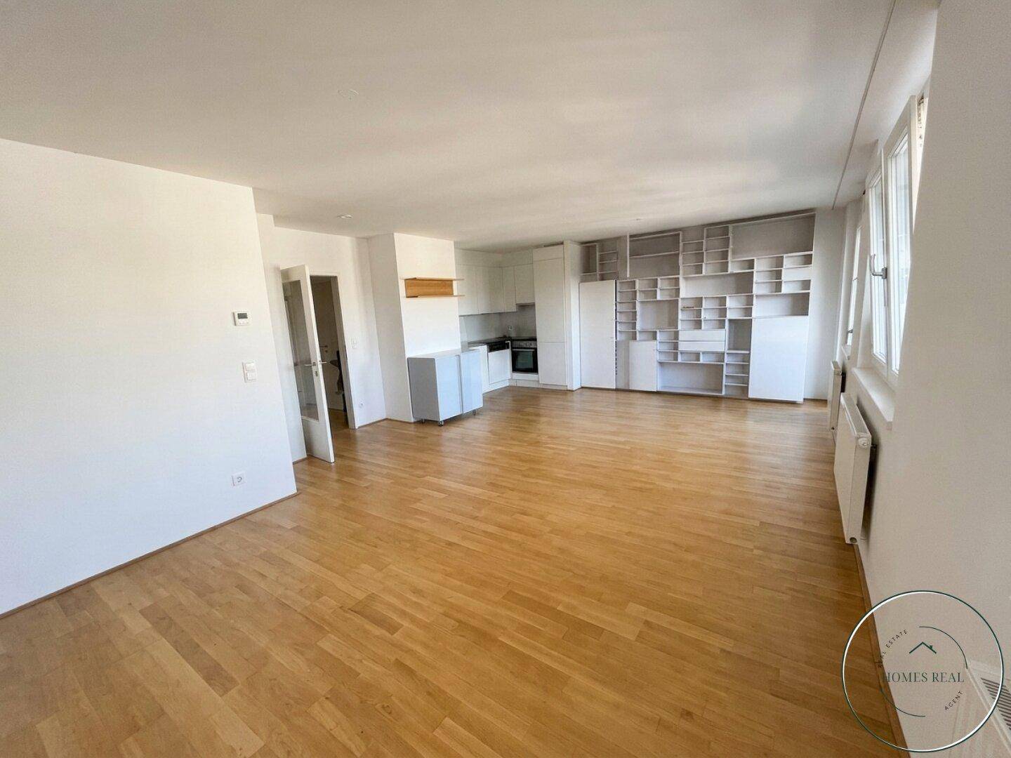 Geräumiger offener Wohn-Essbereich mit Holzboden und vorbereiteter Küchenzeile, ideal für individuelle Gestaltung.