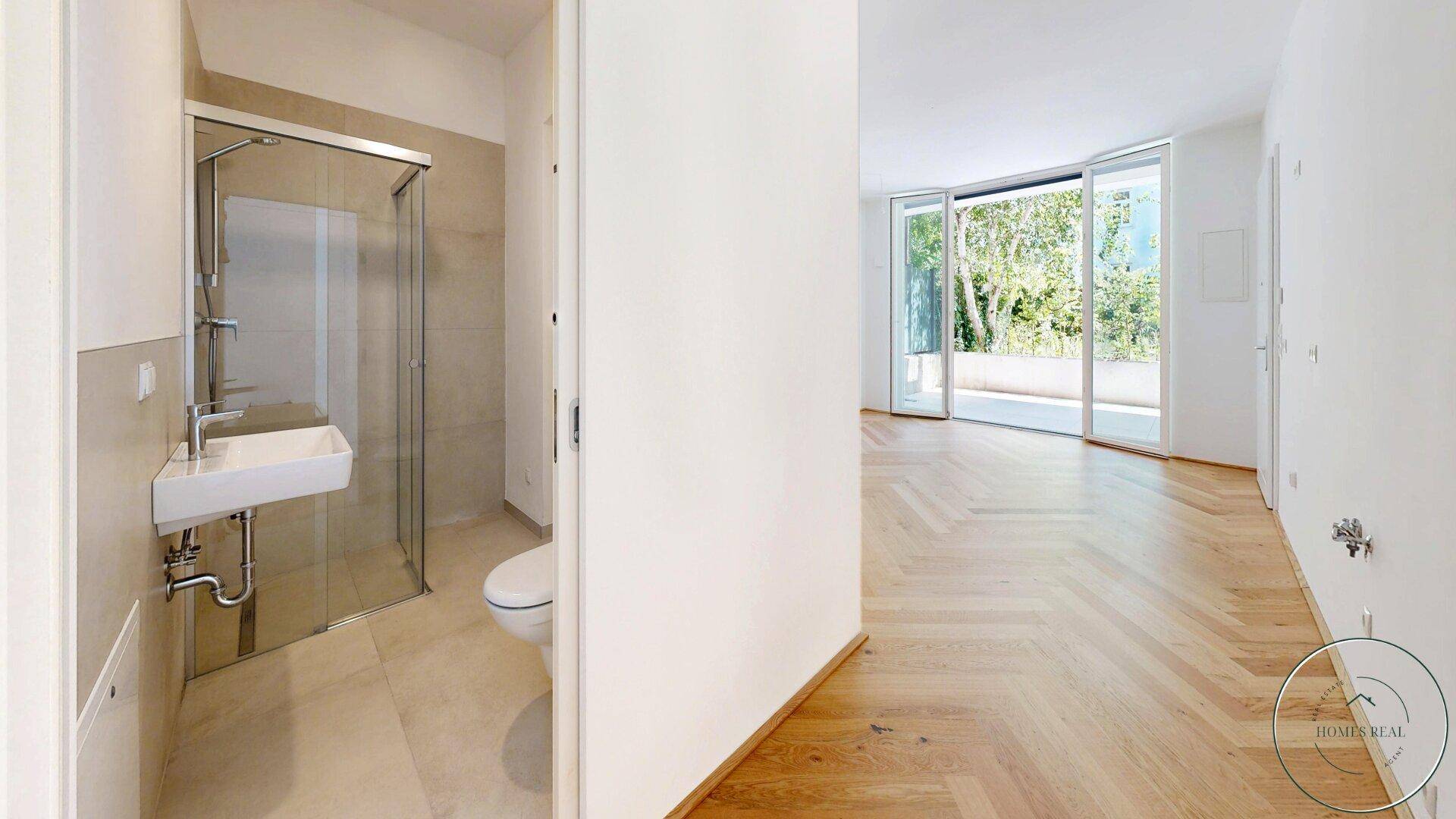 Modernes Badezimmer mit Dusche, WC und Waschbecken, angrenzend an einen hellen Flurbereich.