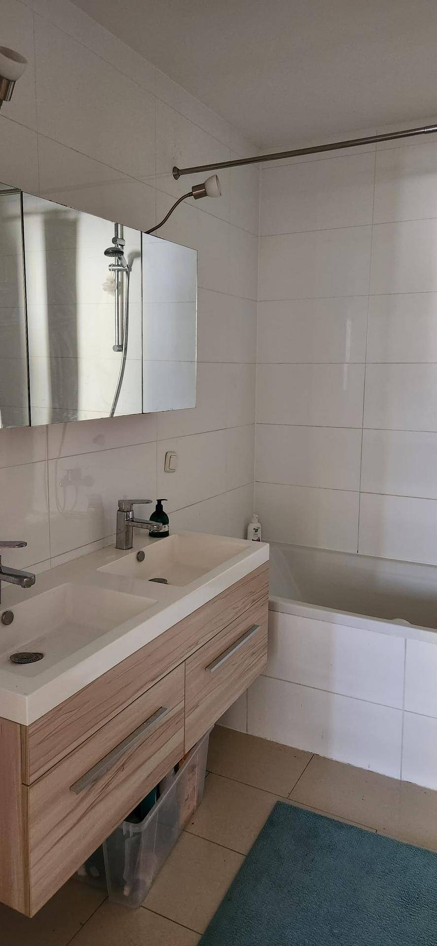 Modernes Badezimmer mit Doppelwaschbecken, Spiegelschrank und einer Badewanne mit Duschvorrichtung.