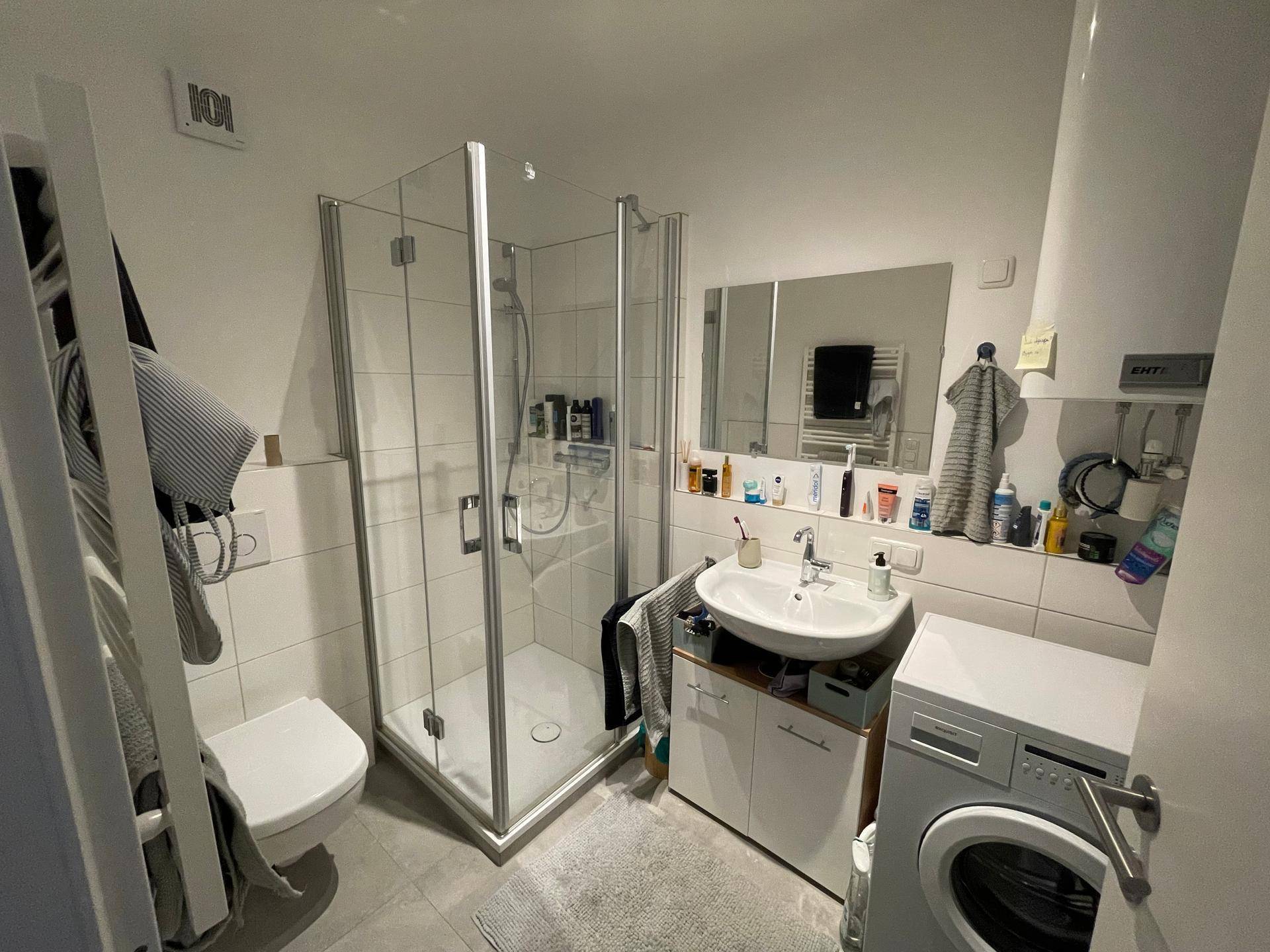 Helles Badezimmer mit Duschkabine, Waschbecken, WC und Handtuchheizkörper.