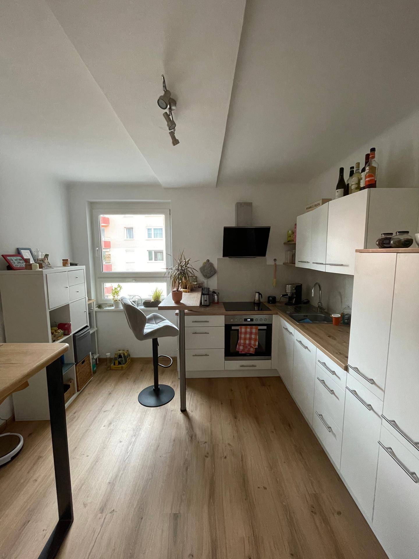 Moderne Einbauküche mit weißen Schränken, Holz-Arbeitsplatte und integrierten Geräten.