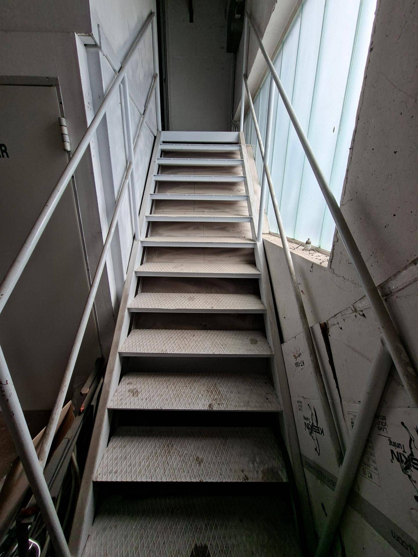 Robuste Metalltreppe mit Geländer, die zu einer oberen Ebene führt.