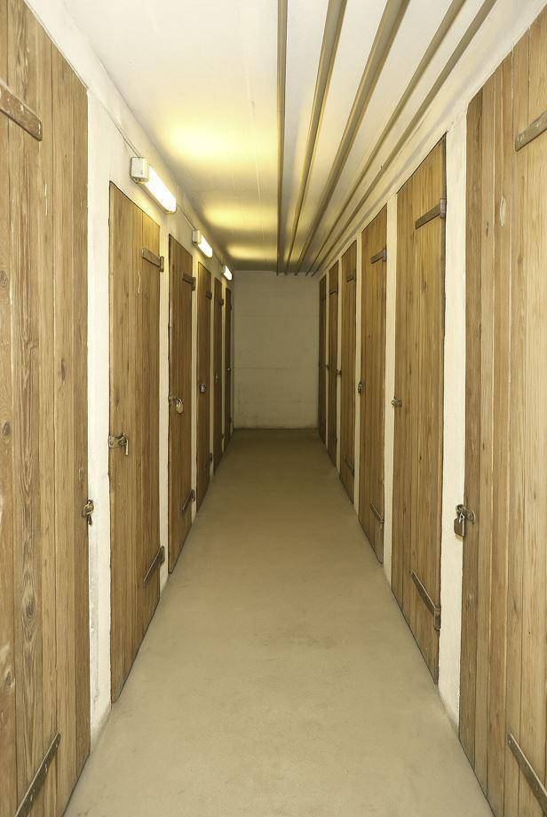 Langer Kellergang mit vielen Holzabteilen für zusätzlichen Stauraum.