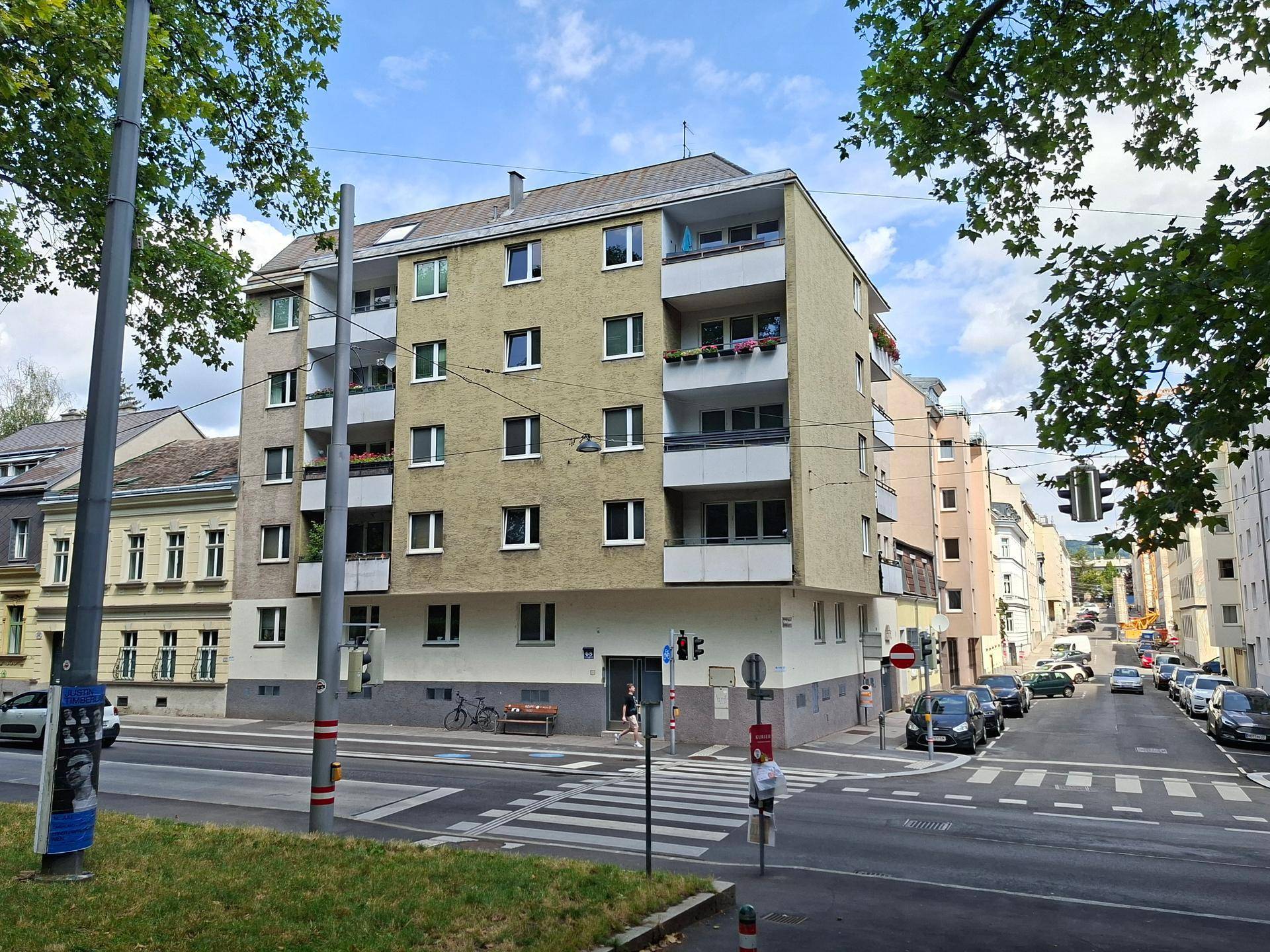 Mehrfamilienhaus an einer belebten Straße mit Balkonen und vielen Fenstern.