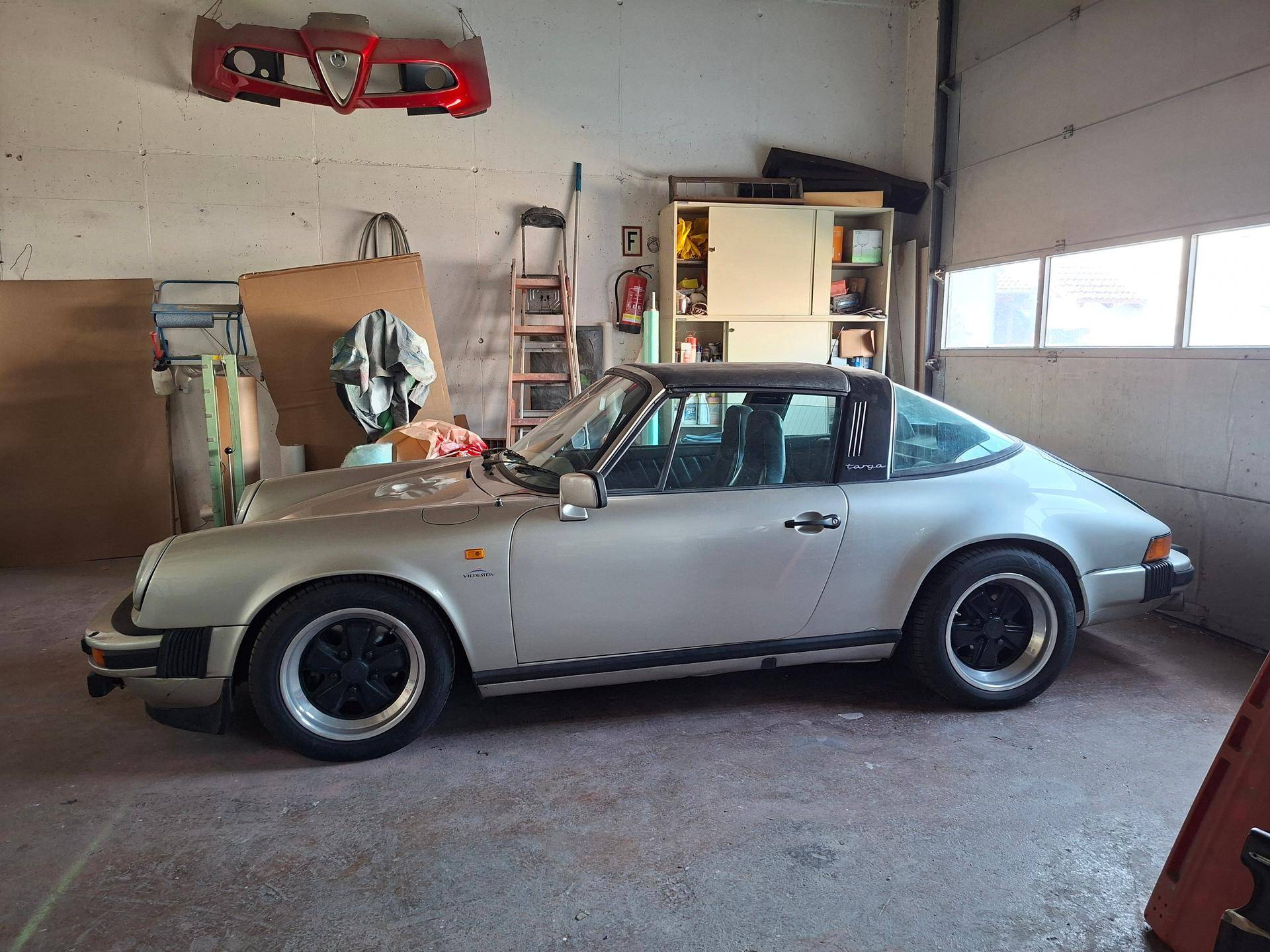 Seitenansicht eines klassischen silbernen Porsche Targa in einer geräumigen Werkstatt.
