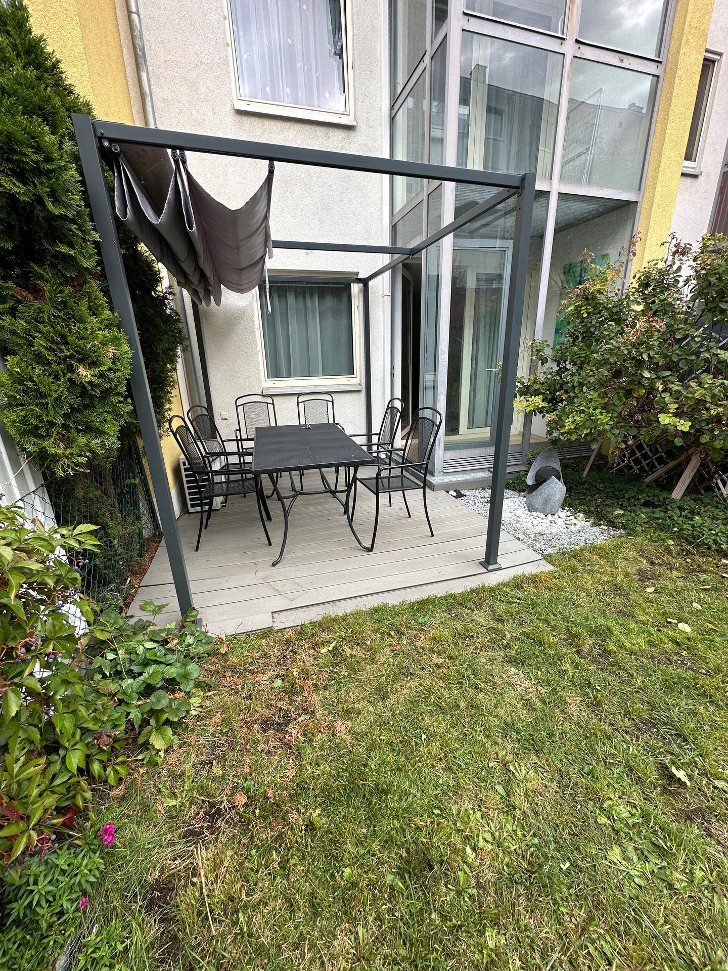 Möblierte Terrasse mit Pergola und Gartenblick, ideal für entspannte Stunden im Freien.