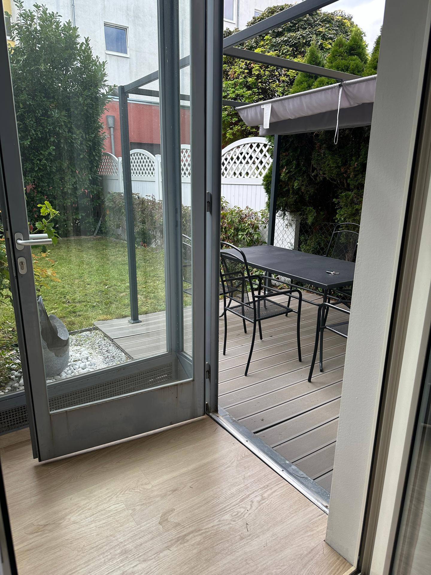 Zugang zur Terrasse mit Holzboden und Blick in den grünen Gartenbereich.