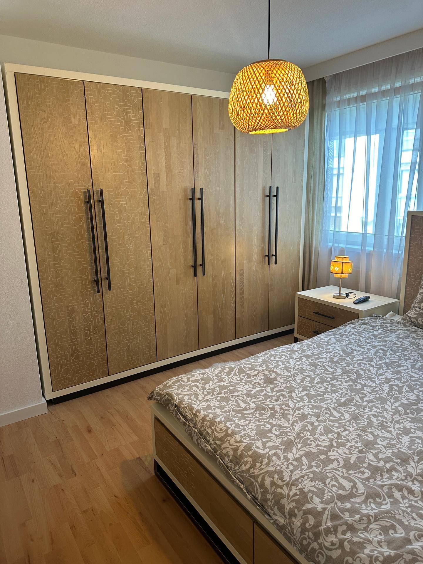 Schlafzimmer mit geräumigem Einbauschrank aus Holz und hellem Parkettboden.