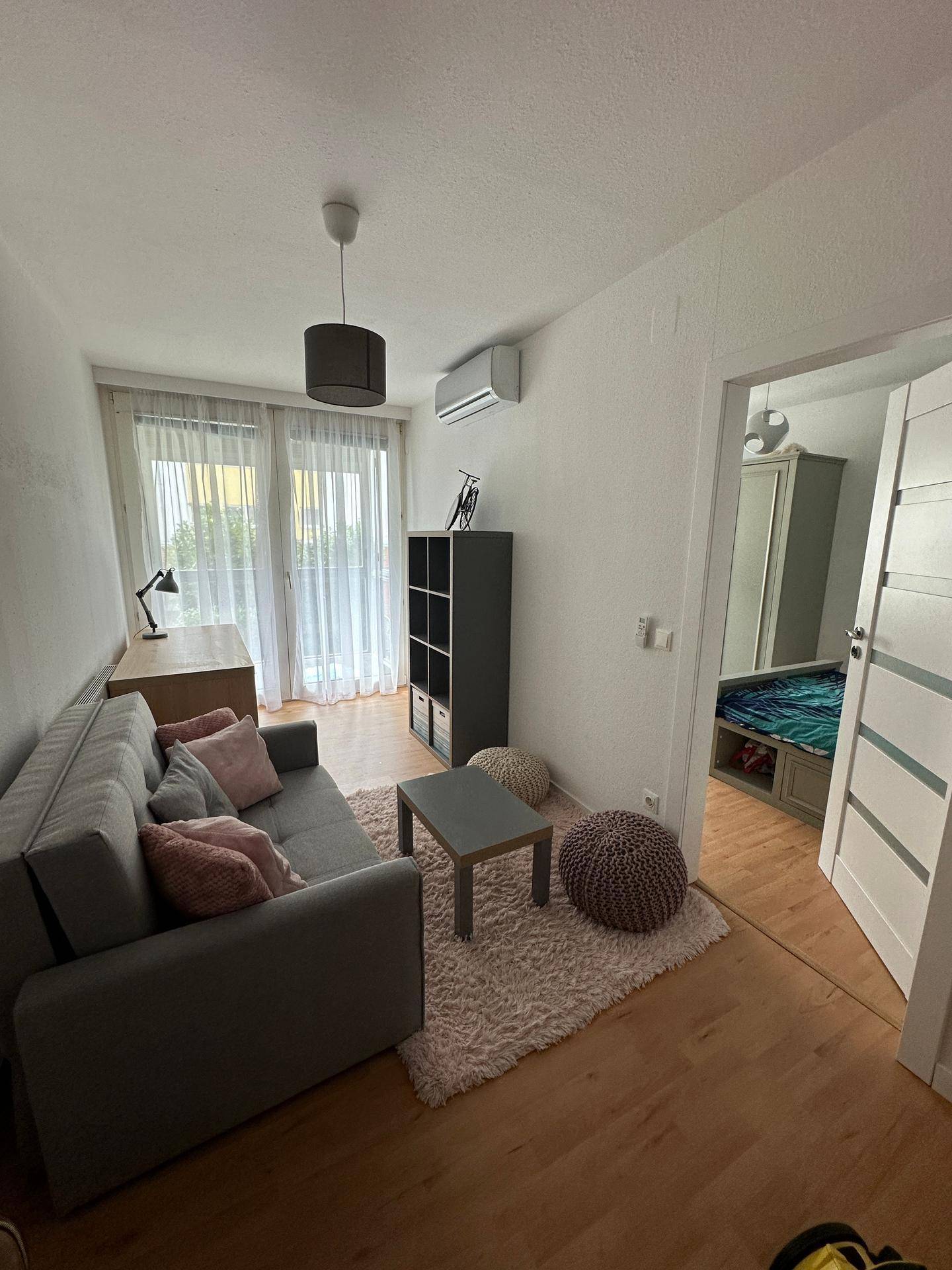 Helles Zimmer mit Sofa, Schreibtisch und Klimaanlage, ideal als Arbeits- oder Gästezimmer.