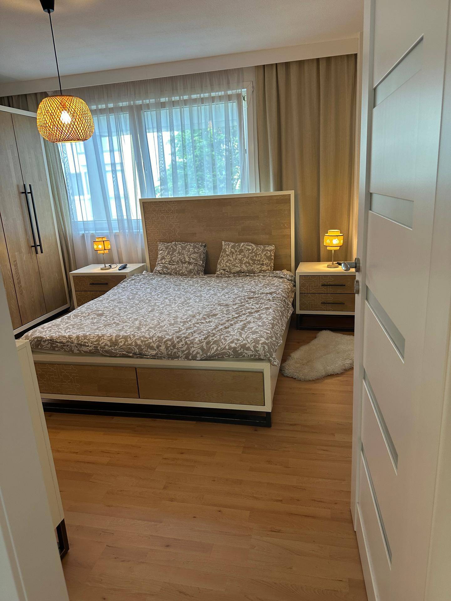 Gemütliches Schlafzimmer mit Doppelbett, Holzmöbeln und großem Fenster für viel Tageslicht.