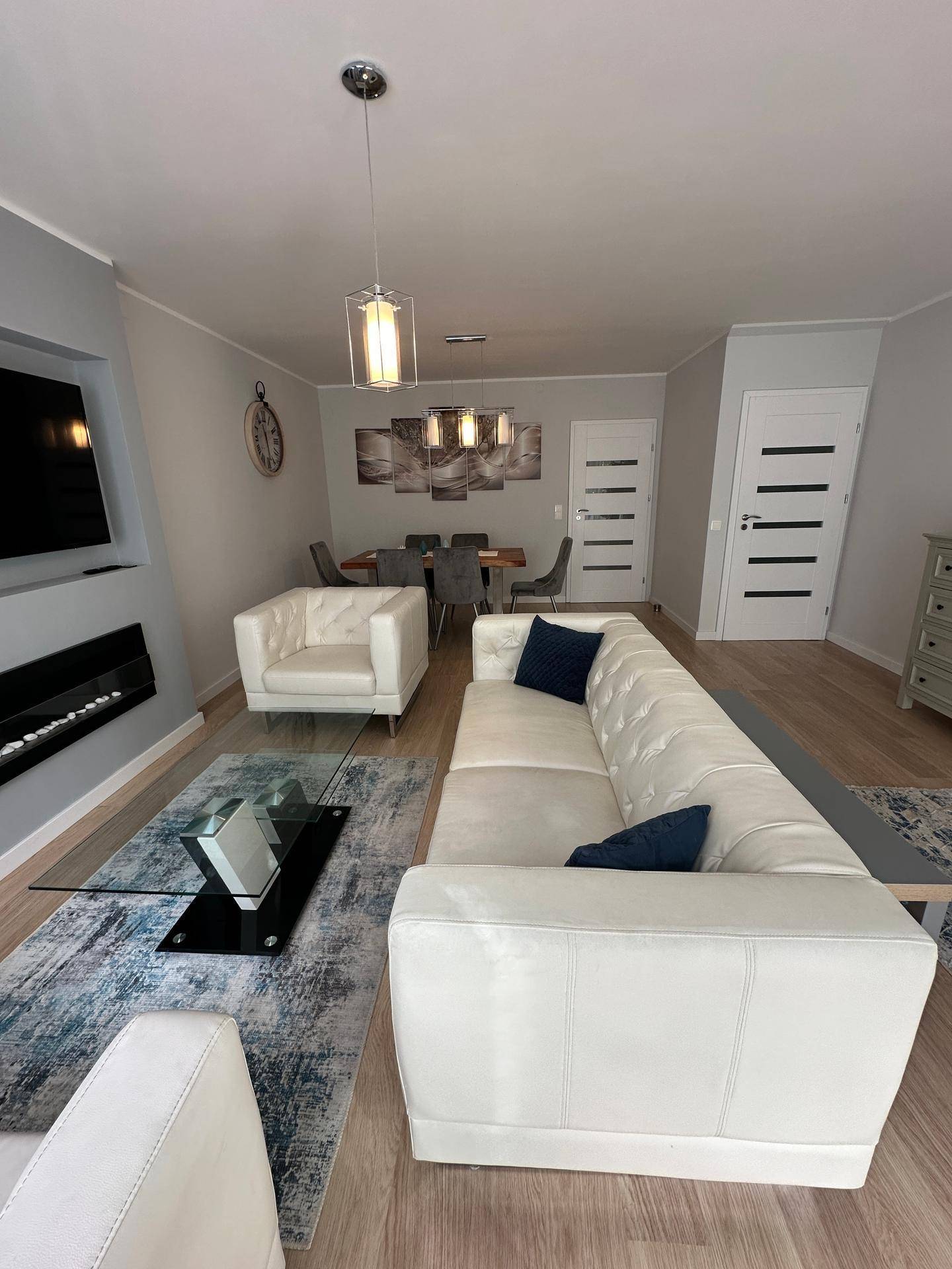 Gemütlicher Wohnbereich mit weißem Sofa, modernem Couchtisch und Blick auf den Essbereich.