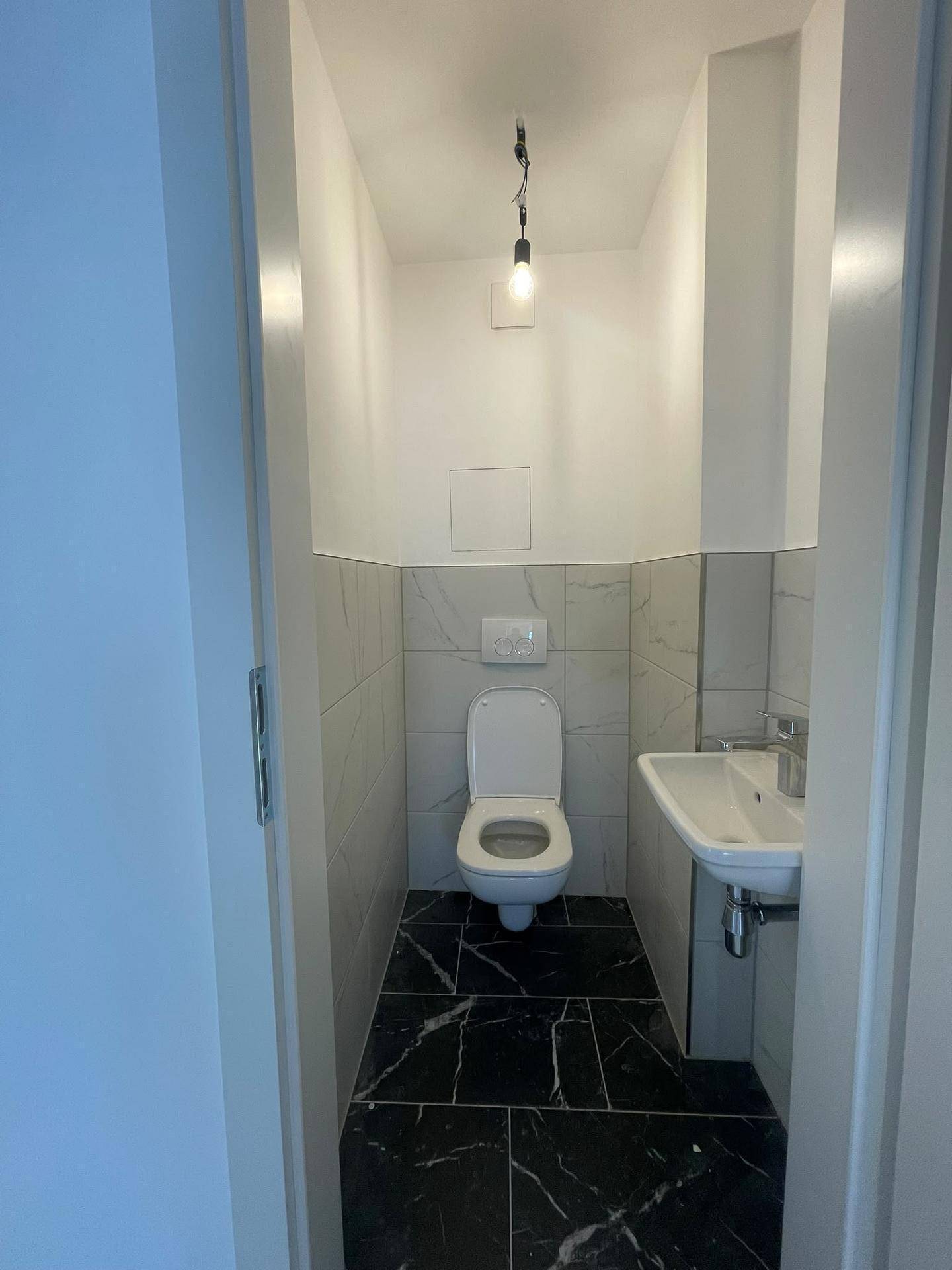 Kleines Gäste-WC mit modernem Fliesenboden und wandhängendem WC.