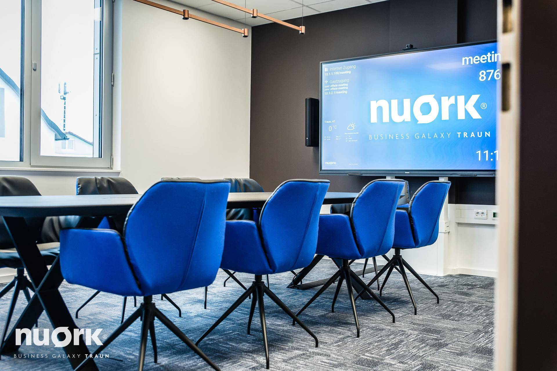 Detailansicht des großen Bildschirms in einem Konferenzraum, der Informationen und Präsentationen anzeigt.
