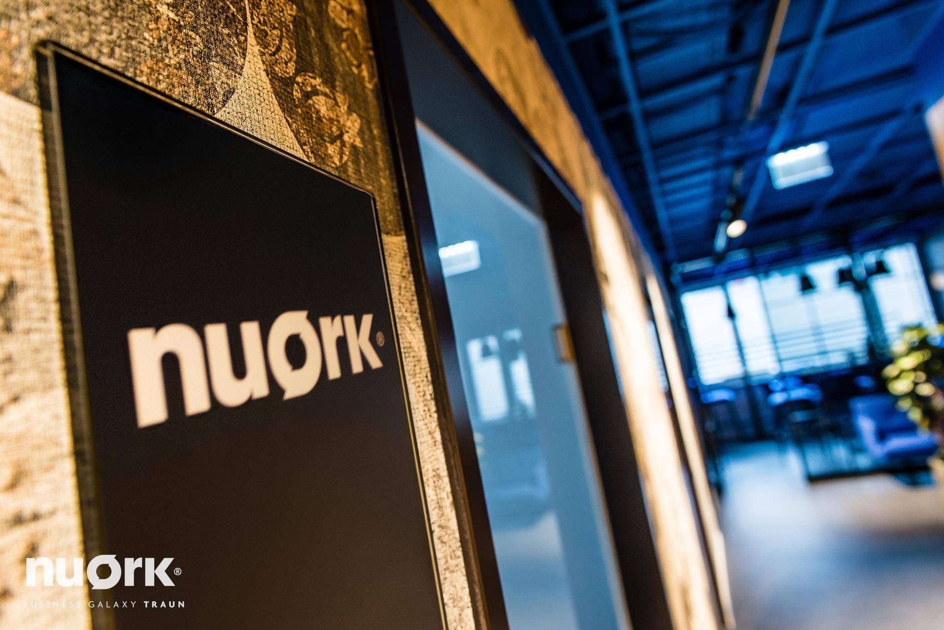 Moderner Flur mit einer Glastür, die das "nuork"-Logo trägt und einen Einblick in den Raum gewährt.